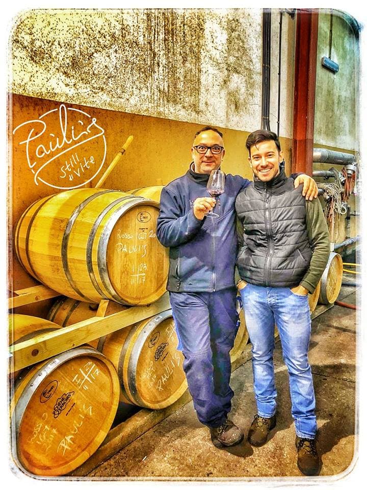Zwei Winzer verkosten Wein vor dem Hintergrund von Holzfässern in Paulis.