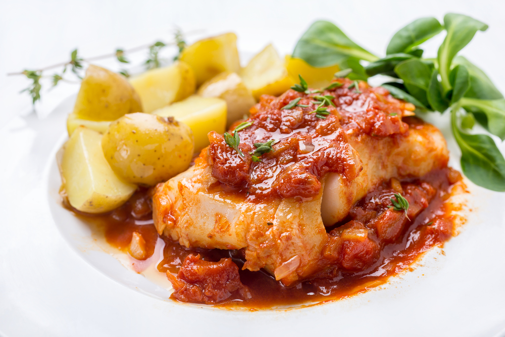 Morue cuite dans une sauce tomate garnie de pommes de terre nouvelles bouillies